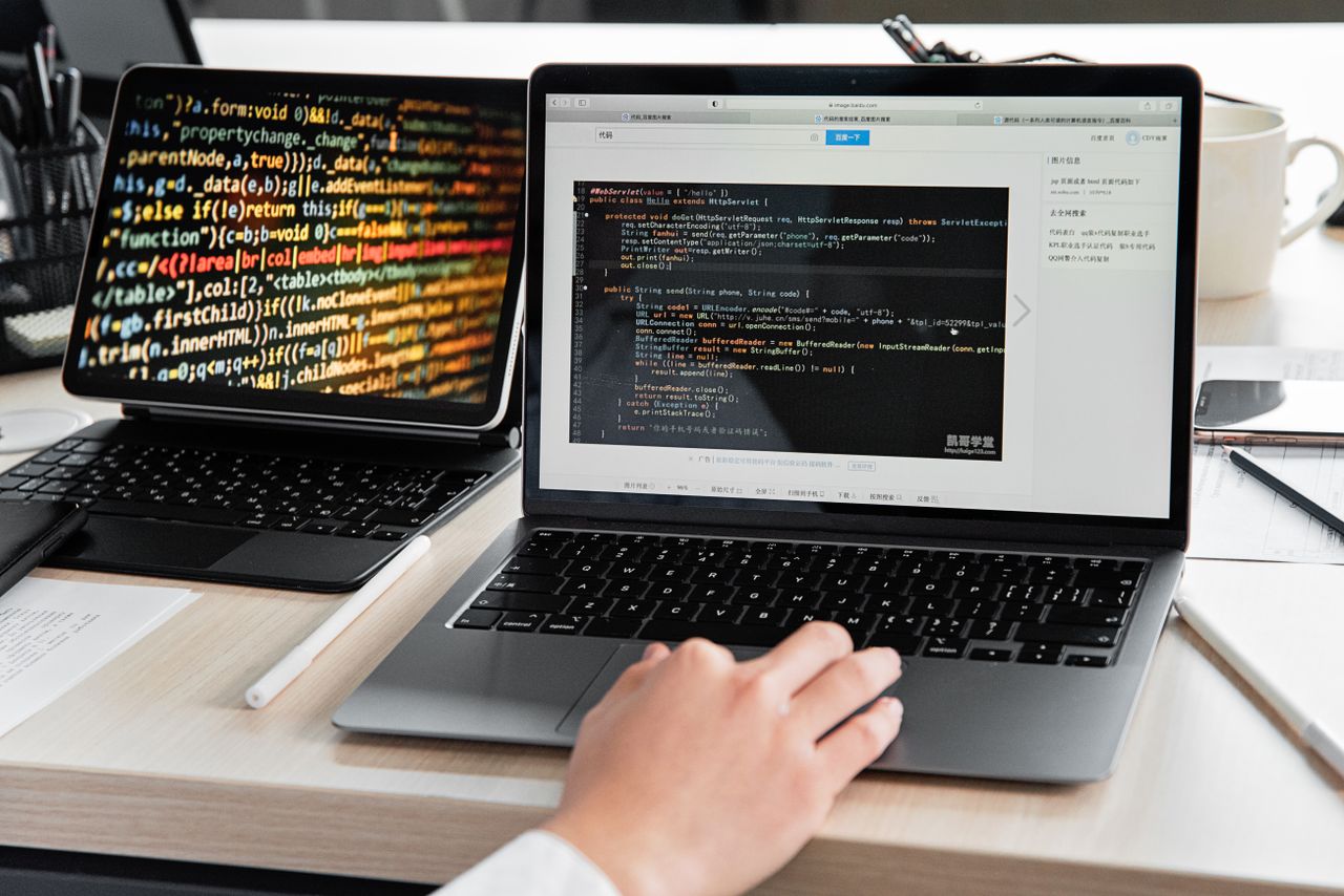 Home A developer writing code on a laptop, displaying programming scripts in an office environment.
